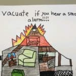 "Evacuate if you hear a smoke alarm" hand drawn image of a house on fire and a person wearing a red hat that says "Fire Safety Week" and a red shirt that says "We can help prevent fires." Art by Matthew B.