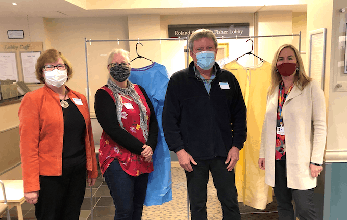 Sarah Shippee, vice president of the Rotary Club of the Deerfield Valley, and Joe Long, treasurer, pose in front of disposable isolation gowns along with Andrea Seaton, Chief Development Officer at Grace Cottage Family Health & Hospital (left) and Gina Pattison, director of Development and Marketing at Brattleboro Memorial Hospital (right).