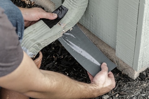 Wrap waterproof tape around the leak and smooth it around all of the gutter ridges for a tight seal