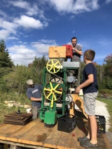 Michael Huck (left) with Mount Holly Selectman Jeff Chase (right) test run the over 100-year-old cider press with 9-year-old Parker Chase directing the whole operation. Photo by Craig Tomkinson