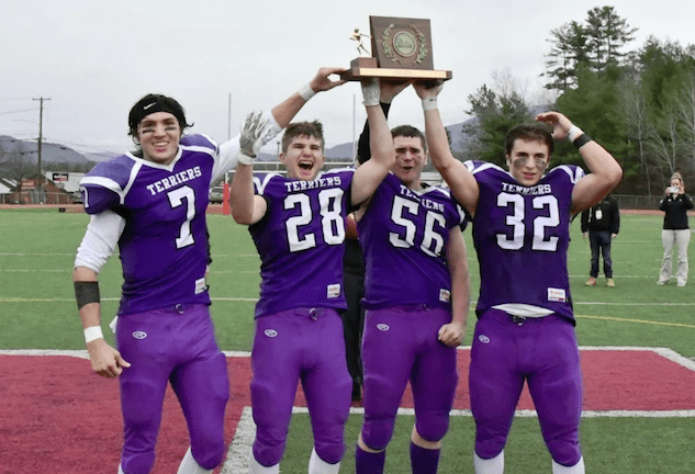 Bellows Falls' Jon Terry (7), Harrison Gleim (28), Patrick Barbour (56), and Jeb Lober (32) hoist the Division II championship trophy after beating Mount Anthony on Saturday at Alumni Field in Rutland. Photo by Doug MacPhee